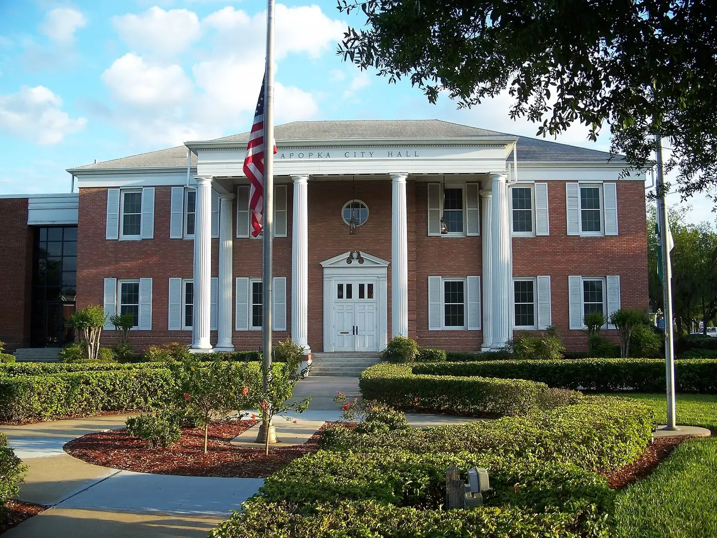 Apopka City Hall, a brick building with white columns and an American flag