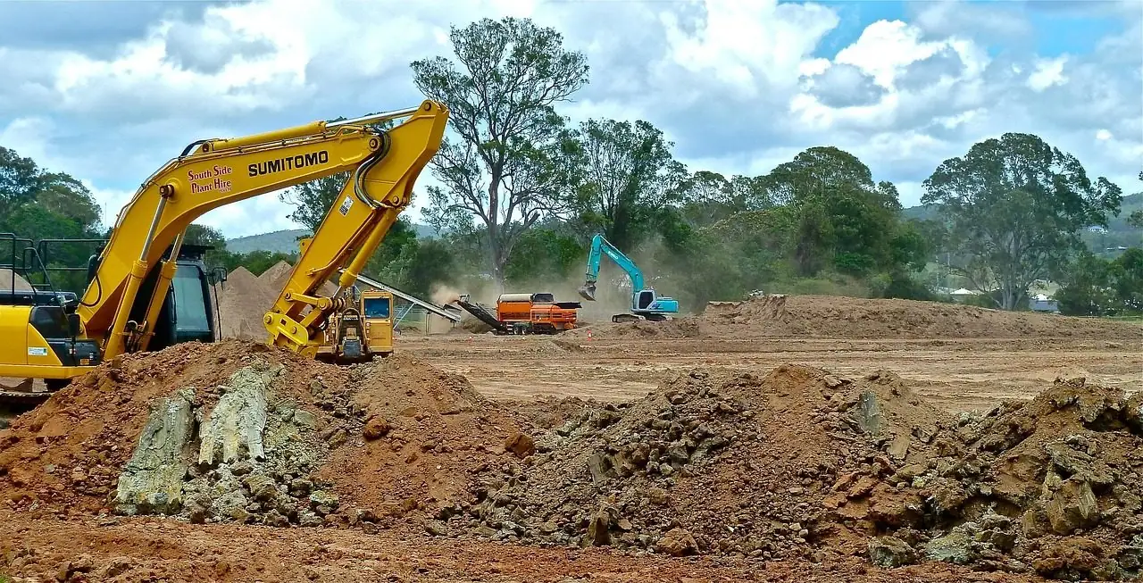 Bulldozer pushing soil and debris across a cleared area