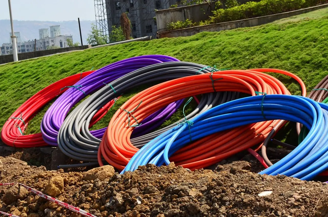 Coils of red, blue, purple and gray conduit on dug-up ground