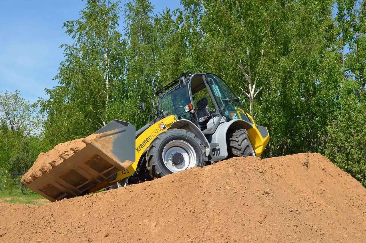 Wheel loader with its bucket raised on top of a mound of sand